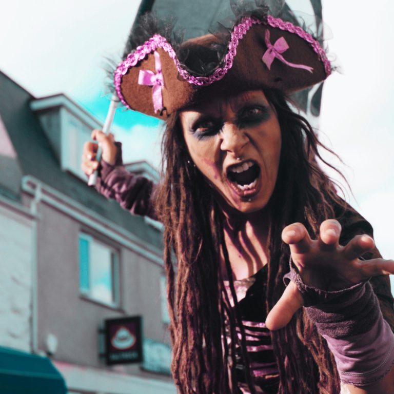 A pirate-costumed participant reaches towards the camera with an open-mouthed expression. Newquay Zombie Crawl 2024.